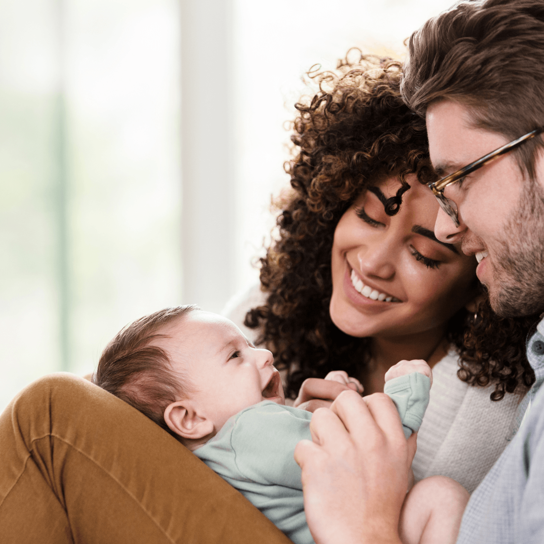 Young man with a baby on his lap, with a woman smiling beside him.