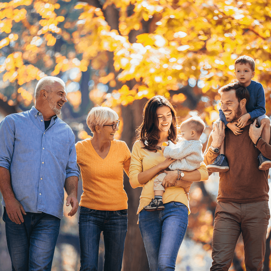 Multi-generational family walking through autumn park, symbolizing support at every life stage