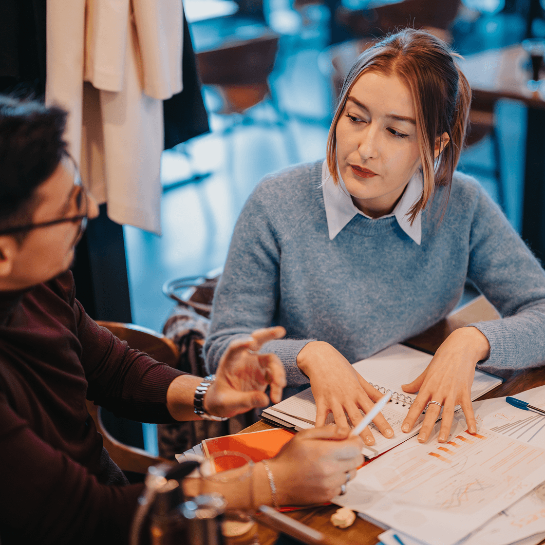 Two people reviewing financial documents and graphs together in a casual meeting setting
