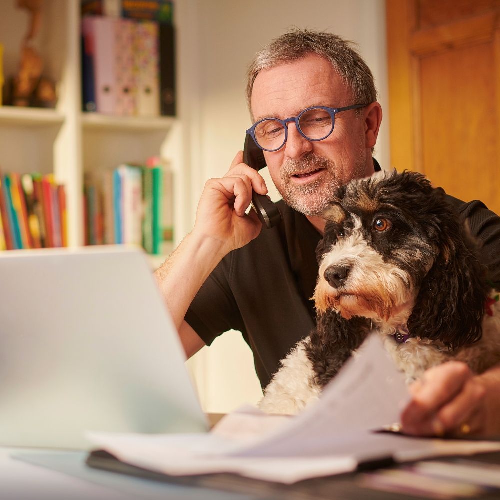 Business man on phone with dog by his side