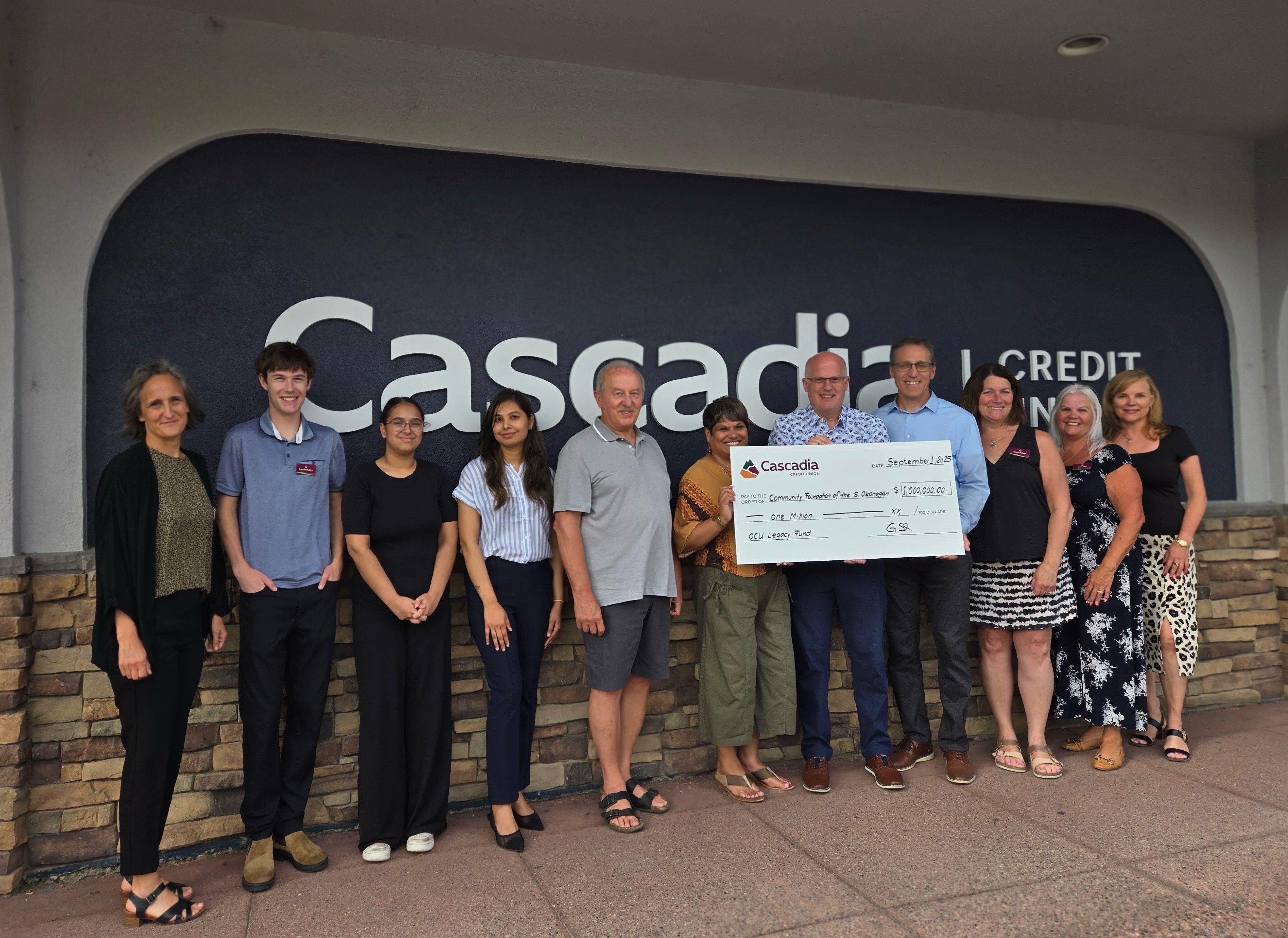 group of people in front of a building presenting a cheque