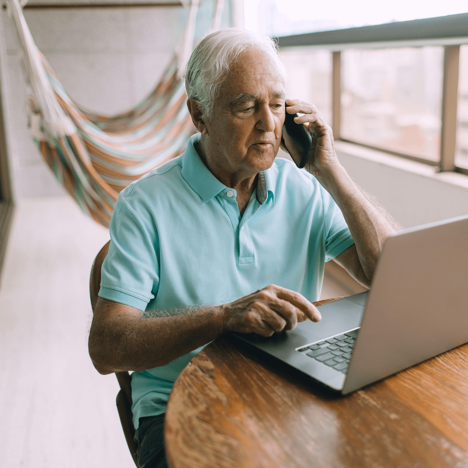 Older man on a laptop, speaking on the phone.