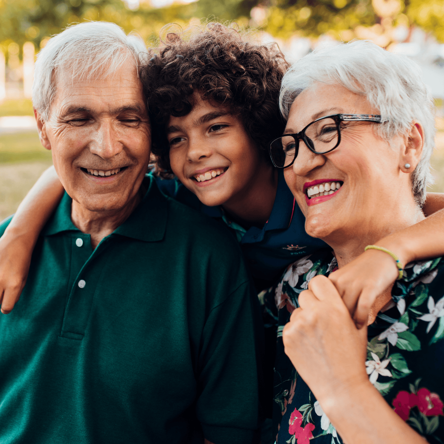 Young boy with his arms around grandparents.